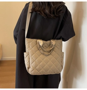 Detail showing khaki quilted tote bag with side pocket and adjustable strap worn on shoulder