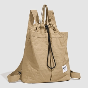 Detail of khaki nylon drawstring backpack showing the dual front pockets and texture
