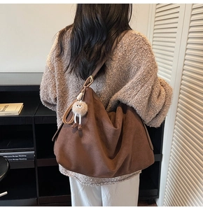Sac fourre-tout en daim marron porté à l'épaule avec un pendentif peluche mignon