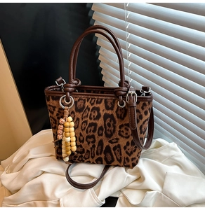 Detail of leopard print bucket bag with leather strap and wooden bead charm accessory