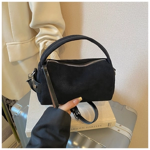 Detail einer schwarzen matten Zylindertasche mit elegantem Griff und Lederriemen