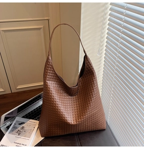 Detail of dark brown woven leather tote bag with checkerboard pattern and long shoulder strap