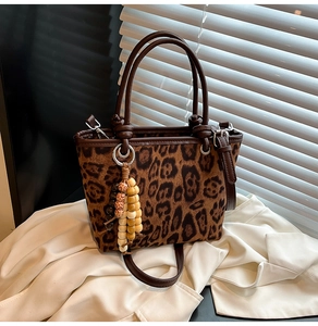 Detail of leopard print bucket bag featuring brown leather trim and wooden bead charm