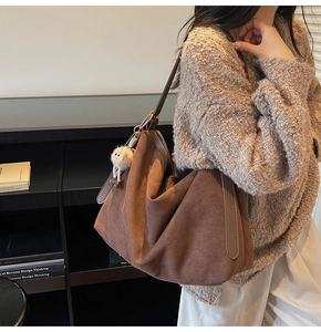 Détail du sac cabas en daim marron avec pendentif en peluche et large bandoulière en cuir