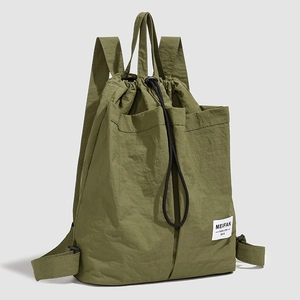 Detail of army green nylon drawstring backpack featuring textured fabric and brand label
