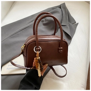 Detail of a retro brown oil wax leather bowling bag with vintage wooden bead charm