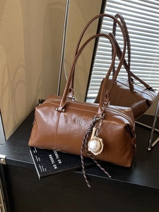Vintage brown leather Boston bag with polished finish and decorative baseball keychain