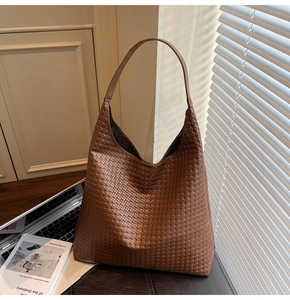 Macro view of brown woven leather texture on a hobo tote bag in a home office setting