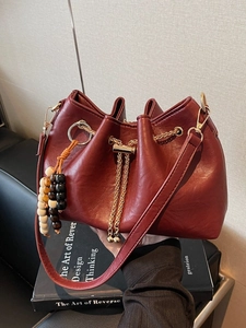 Burgundy faux leather drawstring bucket bag with beaded charm and gold chain strap