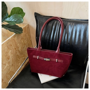 Detailed close-up of burgundy tote bag with buckle strap on a minimalist background