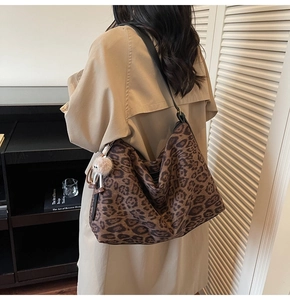 Sac hobo léopard avec bandoulière et breloque peluche porté sur un long manteau beige chic