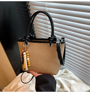 Detail of leopard print bucket bag with beaded charm and black straps on fabric background