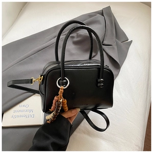 Detail of a black leather mini bowling bag with a vintage beaded charm and logo imprint