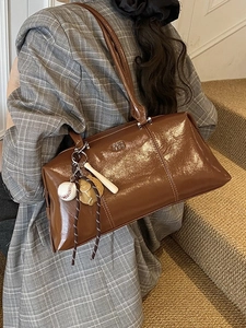 Retro brown polished leather hobo shoulder bag with baseball charms on a model