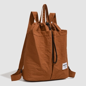 Detail of brown drawstring backpack showing crinkled nylon fabric and brand label