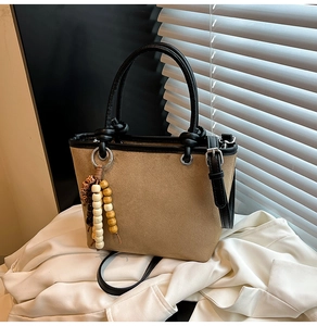 Detail of khaki suede bucket bag featuring leopard trim and boho beaded tassel accent