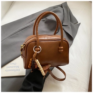 Close-up of retro brown bowling bag with wood bead pendant and adjustable strap details