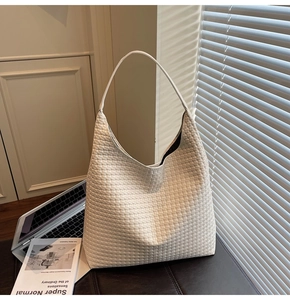 Close-up of white woven tote bag with intricate geometric texture on a leather seat