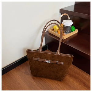 Close-up of a dark brown suede tote bag featuring a leather strap and silver metal buckle