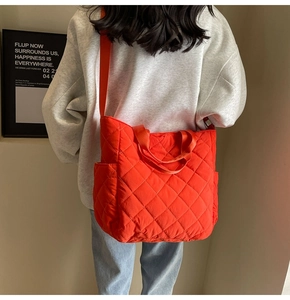 Detailed back view of a large orange quilted tote bag on a model in a minimal setting
