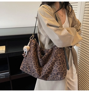 Détail du sac hobo léopard avec boucle dorée et breloque en peluche sur un manteau