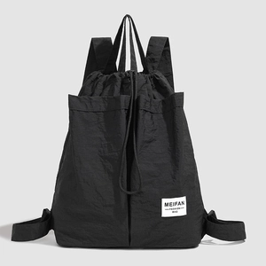 Detail of black nylon drawstring backpack featuring top handles and side pockets