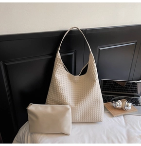 Close-up of beige woven tote bag with matching pouch on a minimalist desk setting