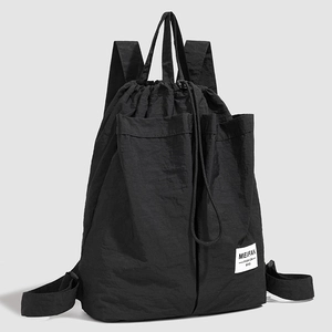 Close-up of a black drawstring backpack showing textured nylon fabric and front pockets