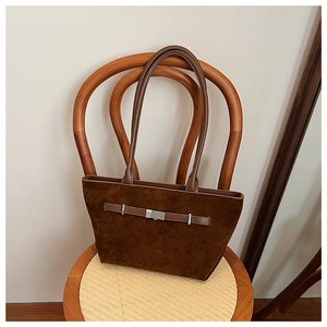 Detail of vintage brown suede tote bag with leather straps on a woven chair