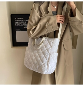 Dettaglio della borsa shopper bianca trapuntata indossata da una modella con trench kaki