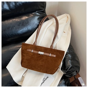 Detailed texture of brown suede tote bag featuring leather straps and silver buckle detail