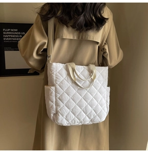 Detail of white quilted tote bag with diamond pattern and side pocket on trench coat