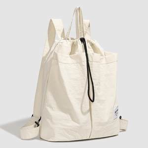 Detail of cream drawstring backpack with adjustable straps and front storage pockets