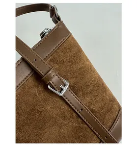 Detail of adjustable silver buckle and brown matte texture on crossbody bucket bag