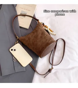 Gros plan du sac seau en daim matelassé avec breloque perlée sur costume gris