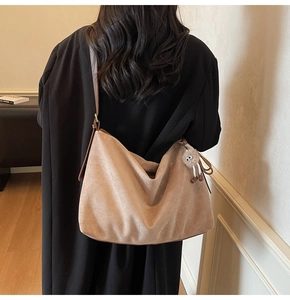 Détail du grand sac hobo en daim marron avec breloque monstre en peluche sur le mannequin