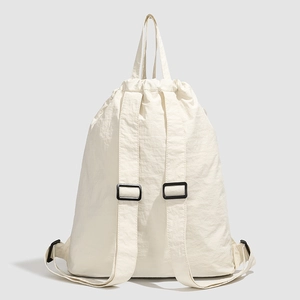 Close-up of off-white drawstring backpack with minimalist nylon texture and buckles