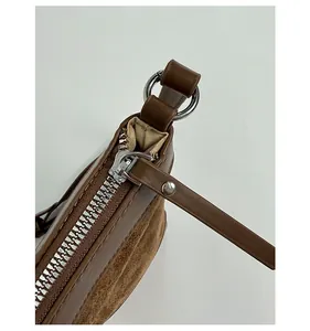 Detailed macro view of the smooth silver metal zipper and brown matte suede fabric