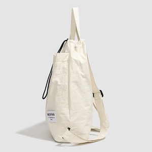 Detail view of large beige drawstring backpack showing texture and side label