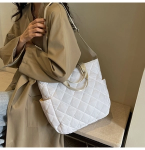 Detail of white quilted tote bag featuring classic diamond stitching and functional side pocket