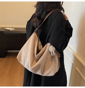 Détail du sac cabas en daim camel avec bandoulière en cuir marron et breloque