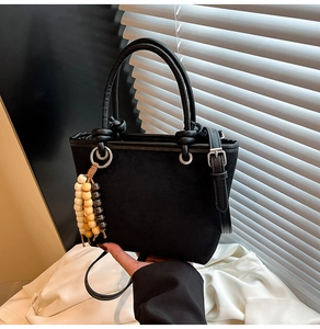 Chic black faux suede bucket bag featuring colorful wooden beads and a top handle strap
