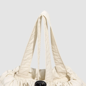 Detail of cream drawstring backpack showing soft crinkled nylon fabric and top handle