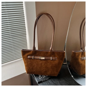 Detailed view of brown suede tote bag featuring a decorative belt buckle and shoulder straps