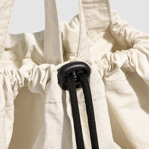 Detailed macro view of cream backpack drawstring closure with black plastic spring toggle