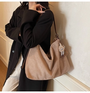 Gros plan sur un grand sac hobo en daim marron avec bandoulière cuir et charm en peluche