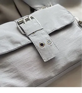 Détail du tissu en nylon gris clair avec texture plissée, œillets argentés et boucle