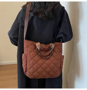 Brown quilted tote bag with diamond pattern shown on model in black winter coat