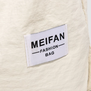 Detail of a white nylon backpack with a stitched MEIFAN FASHION BAG rectangular label