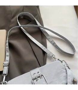 Détail de la bandoulière réglable avec boucles argentées sur le sac en toile gris épuré